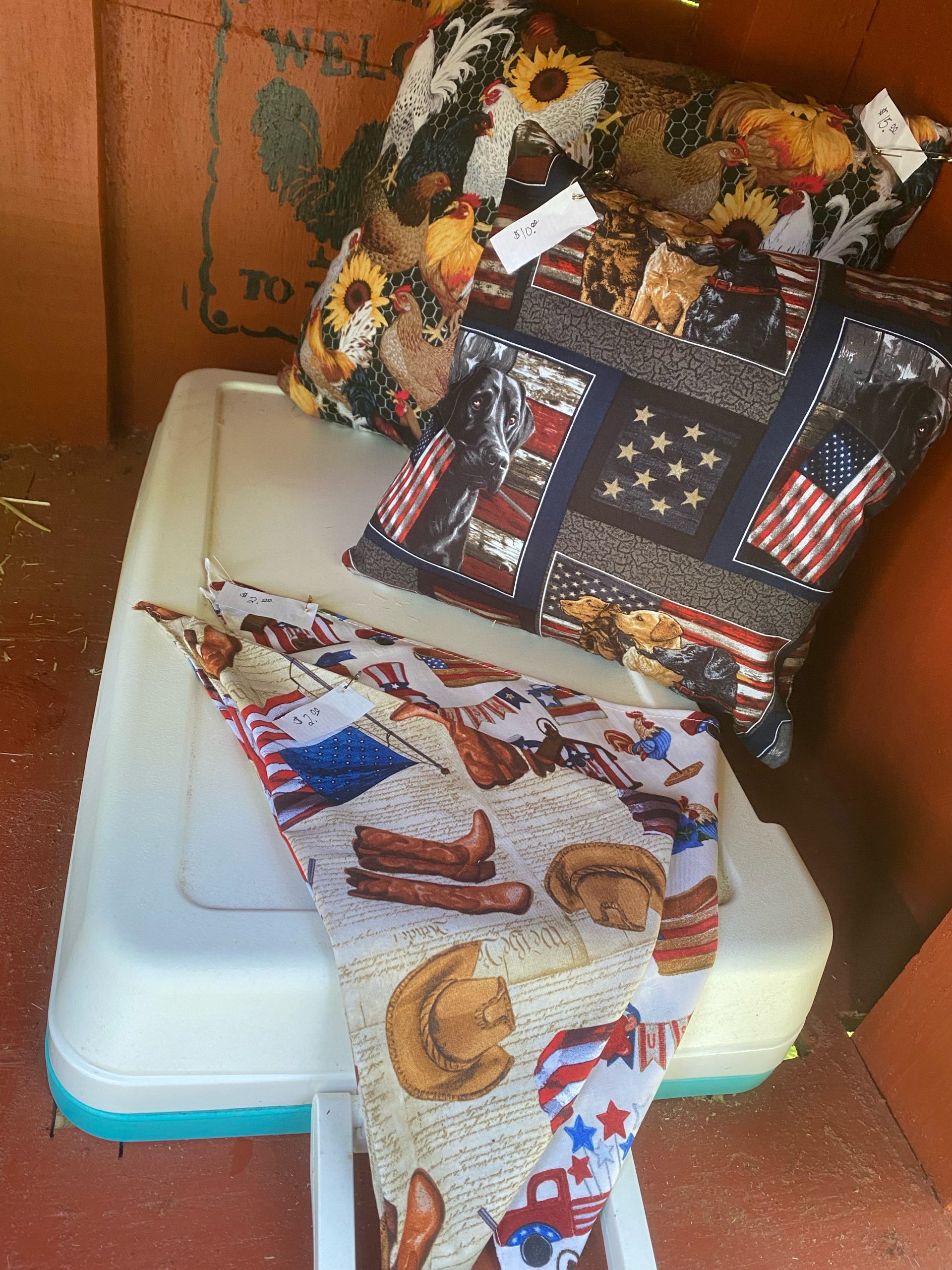 Handmade sunflower-chicken and patriotic dog pillows with western-print bandanas displayed inside the farm stand.